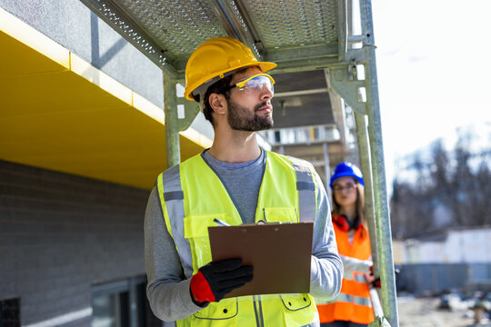 Male and female engineers performing a safety inspection on construction scaffolding.