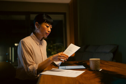 Asian woman working late night reading documents at home