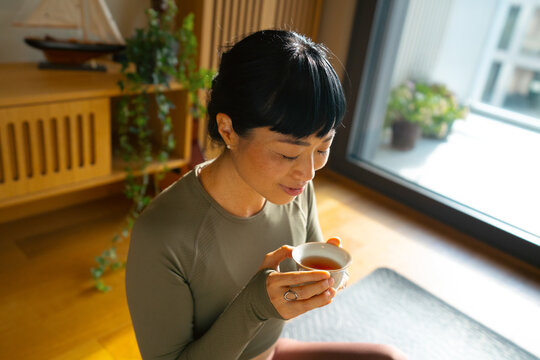 Woman relaxing with tea at home after practicing yoga