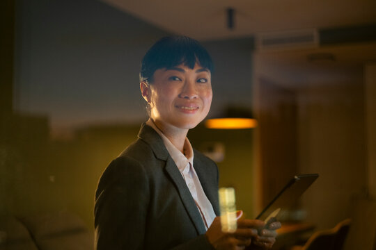Asian businesswoman smiling holding tablet in office