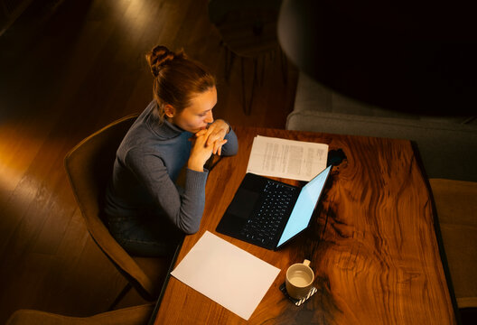 Woman working late at home office studying using laptop