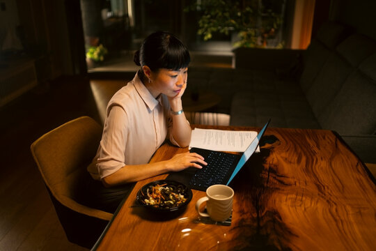 Woman working hard on laptop during home dinner