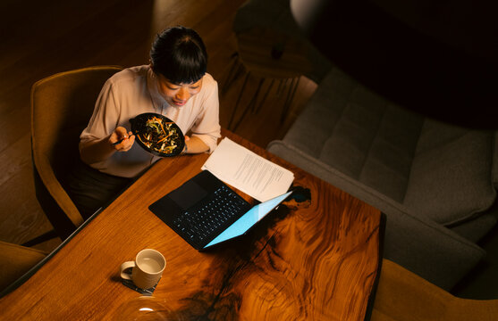 Woman working late eating takeout food at desk