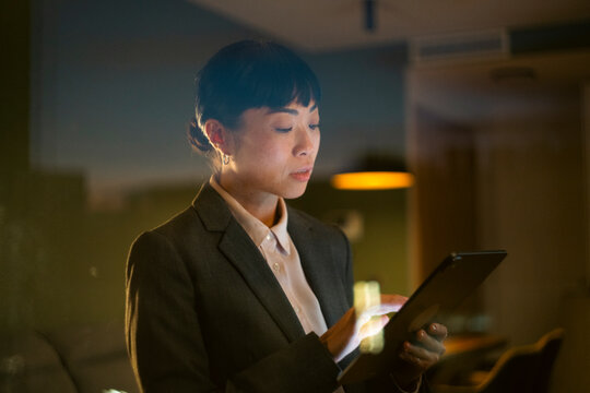 Asian businesswoman working late with digital tablet in office
