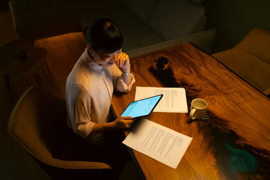 Asian woman working late with tablet and documents