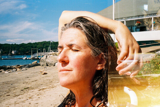 Woman soaking up sun on beach with cat hovering above her