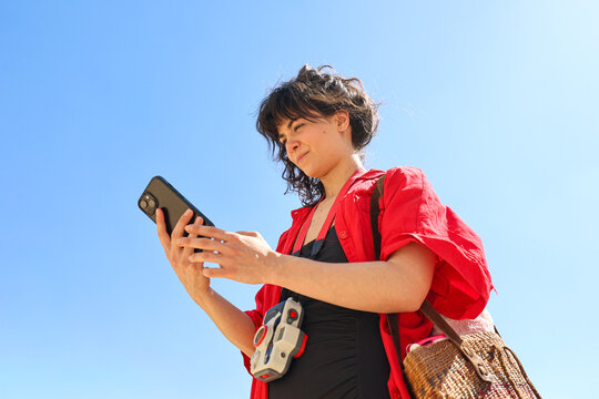 Girl using cell phone against blue sky