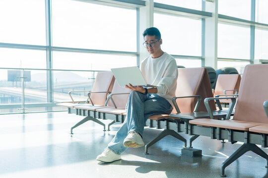 Asian man using laptop at airport