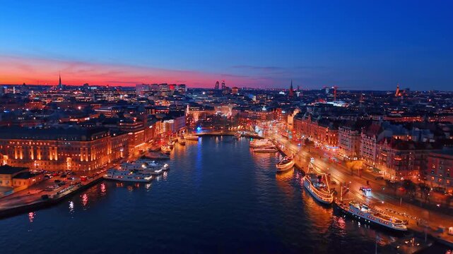 Spectacular luminous waterfronts of Stockholm, Sweden at night. Boats decorated with lights stand at the quay.