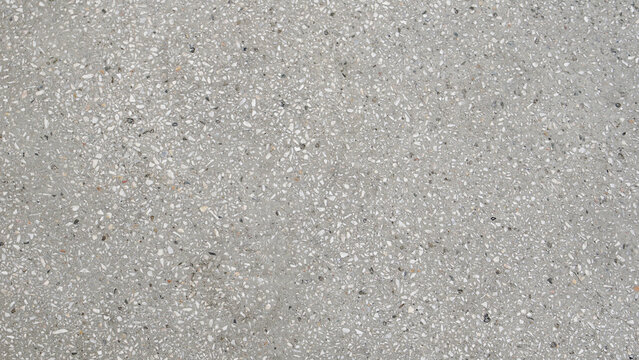 Light gray terrazzo concrete surface with small white and dark stone chips, flat lay texture background.
