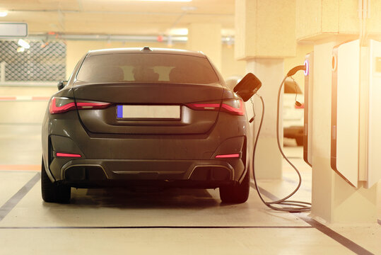 Rear View Of Plug-In Hybrid Electric Vehicle Charging at EV Station in Underground Parking