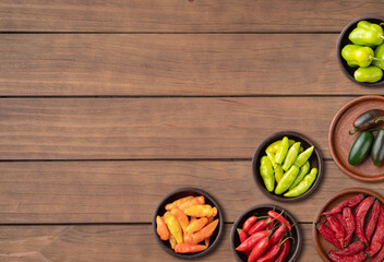 Assorted peppers over wooden table with copy space