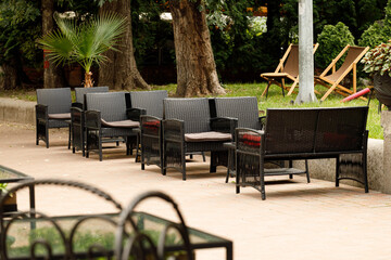 Obraz premium Outdoor cafe seating area with wicker chairs and lounge chairs in the background