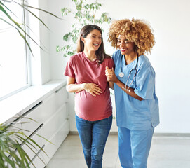 Portrait of a young happy pregnant woman exercising with doctor or nurse during a visit at home or...