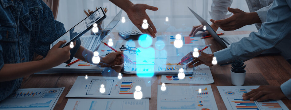 A diverse team engages in a collaborative business meeting, analyzing data and sharing ideas, with digital user icons overlaying a modern workspace. Trope
