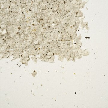 Coffee chaff embedded in recycled paper, brown speckles on off-white, organic texture