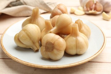 Pickled garlic on light wooden table, closeup