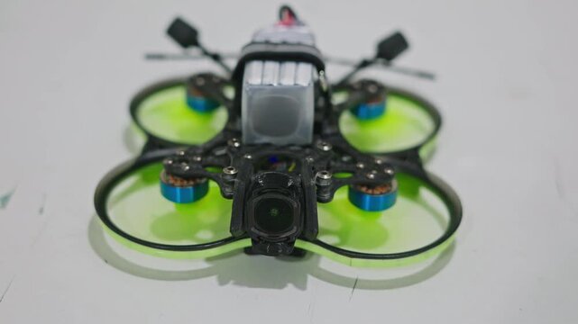 Medium shot of an FPV drone starting to spin its propellers while standing on a flat surface. Motor startup phase, electronic arming and preflight activation. High quality 4k footage