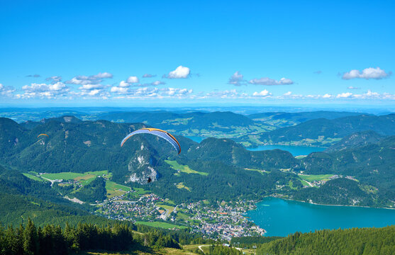 Scenic summer panorama of St. Gilgen and Lake Wolfgang with a paragliding pilot soaring above, Salzkammergut, Austria.