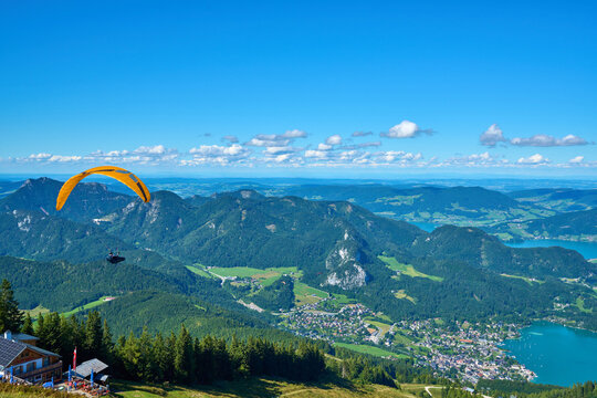 Scenic summer panorama of St. Gilgen and Lake Wolfgang with a paragliding pilot soaring above, Salzkammergut, Austria.