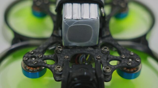 Close-up shot of FPV drone propellers slowing down and stopping. Motor deceleration phase and electronic shutdown sequence on stationary quadcopter. High quality 4k footage