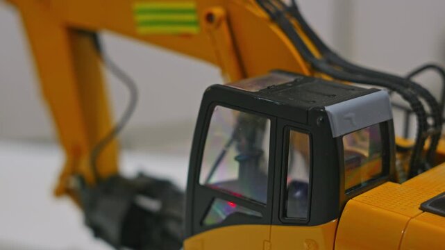 Close-up shot of a toy plastic excavator with blinking red button inside the cabin. Children construction vehicle model and illuminated play feature. High quality 4k footage