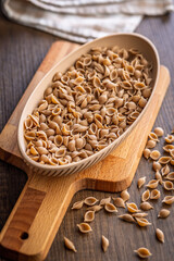 Wholegrain conchiglie pasta in bowl on wooden table.