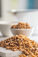 Wholegrain conchiglie pasta on white table.