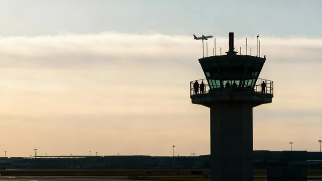 Airport control tower wide shot at sunset with aircraft departing in background