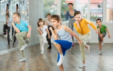 Fototapeta premium Group of preteen girls and boys enjoying active dance movement in modern studio