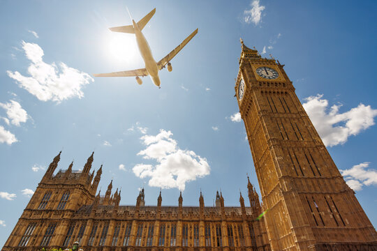 Airplane fly over Big Ben in London under sun, United Kingdom