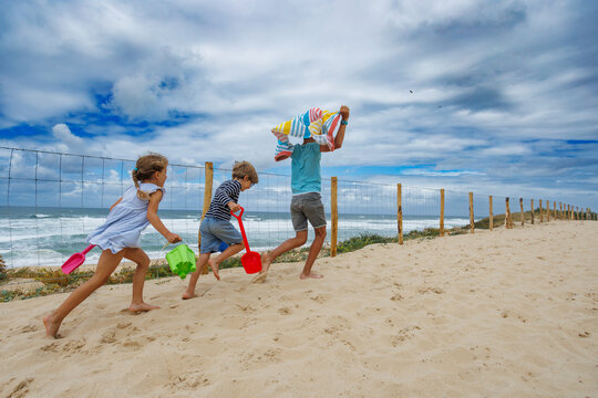 Kids racing to beach with toys and towels in summer vacations