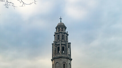 Fototapeta premium White tower against the backdrop of a cloudy evening sky. White church tower against the backdrop of clouds