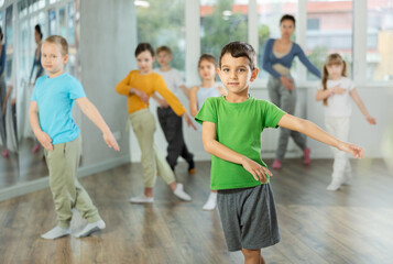 Obraz premium Dynamic little boy training hip hop dance poses with instructor and other attendees of dancing courses