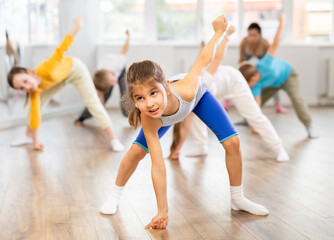 Fototapeta premium Group of children boys and girls with coach warming up before dance class in studio