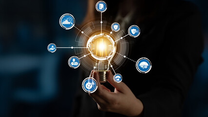 Fototapeta na wymiar A business professional holds a glowing light bulb, symbolizing innovation and technology, with various connected icons representing ideas, solutions, and growth in the digital era. Crux