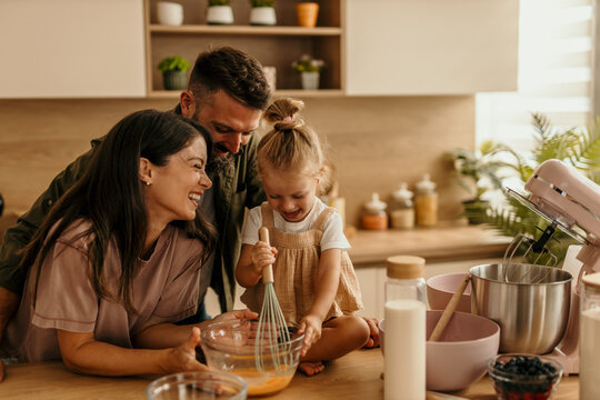 Family cooking together in modern kitchen laughing