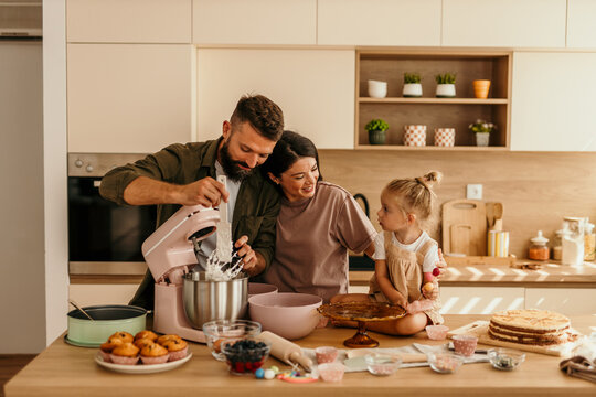 Family baking together in kitchen preparing sweet treats