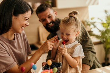 Happy family sharing berries and laughing together