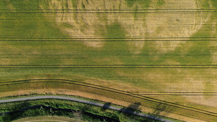 Green and brown fields with road and river seen from the air
