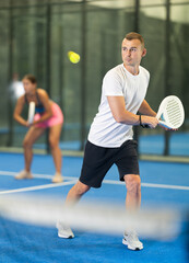 Young woman and young guy in doubles play tennis on tennis court