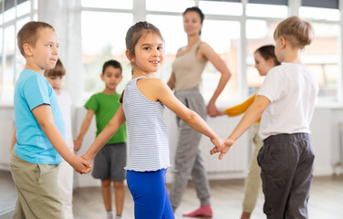 Children holding hands and dancing in a round dance in choreography class