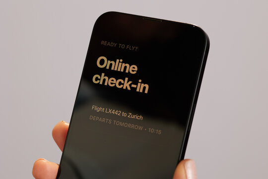 Close-up of a person using a smartphone for online flight check-in to Zurich, highlighting the ease and efficiency of modern digital travel preparation.