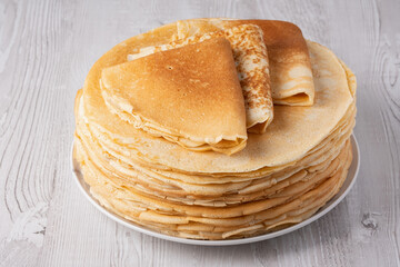 Thin pancakes on a wood table. Homemade crepes, tasty food. Staple of yeast pancakes, traditional for Russian pancake week (Shrove tide). Thin pancake with crispy crust