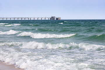 Gulf Shores Alabama Beach With Waves Rolling in and a Pier in the Background During a Clear Day