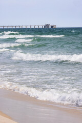 Gulf Shores Alabama Shows Ocean Waves Rolling Onto the Shore Near the Pier on a Sunny Day