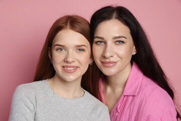 Portrait of mother and her smiling teenage daughter on pink background