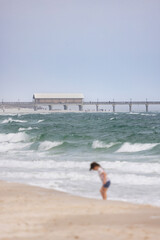 Gulf Shores Alabama Beach Scene With an Intentionally Blurred Child Playing by the Water and a Fishing Pier in the Background