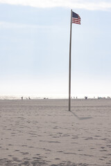 Beach Scene at Gulf Shores Alabama With People Enjoying the Sun and American Flag Standing Tall on the Sandy Shore