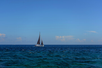 Obraz premium Sailboat on open blue ocean under clear sky in mexico caribbean